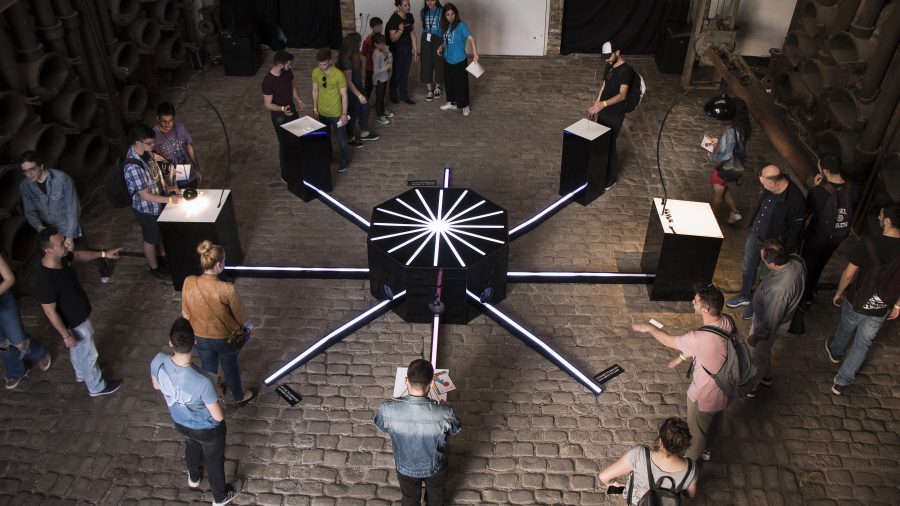 Visitors gather around eight instruments linked by illuminated spokes to a central hub.
